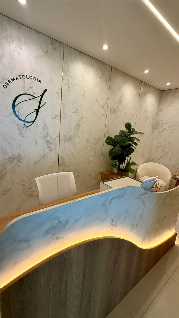 Recepção do consultório da Dra. Giovana Jordão, com balcão iluminado e parede em mármore